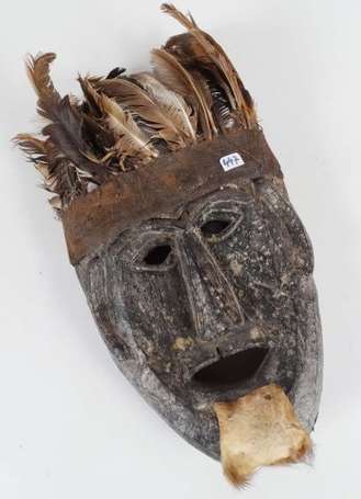 Un masque en bois orné d'une coiffe de plumes et 