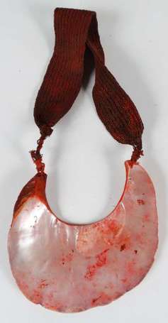 Un pendentif en nacre et fibres à patine rouge. 